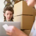 Strategi bisnis reseller online sedang mengemas barang dan memantau pesanan di laptop
