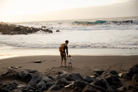 Ibu dan anak kecil sedang menikmati tips liburan dengan anak kecil yang santai di taman pantai