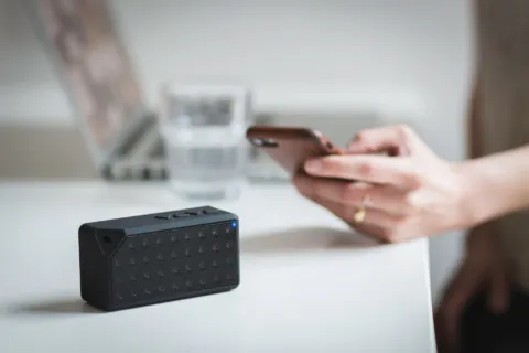 Ilustrasi speaker Bluetooth portabel bersuara jernih sedang memutar musik di meja kerja