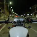 Pengendara mengendarai sepeda motor di jalan raya pada malam hari dengan lampu menyala