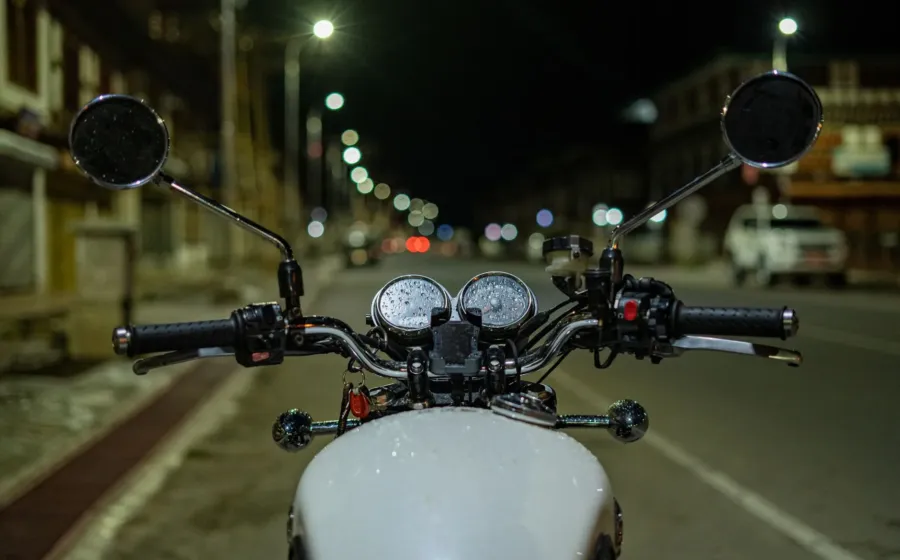 Pengendara mengendarai sepeda motor di jalan raya pada malam hari dengan lampu menyala