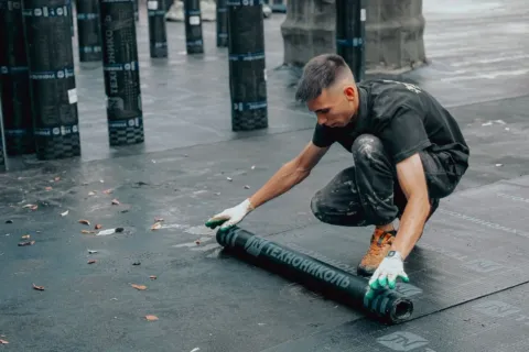 Tukang bangunan sedang memperbaik bagian atap rumah bocor menggunakan cat waterproofing