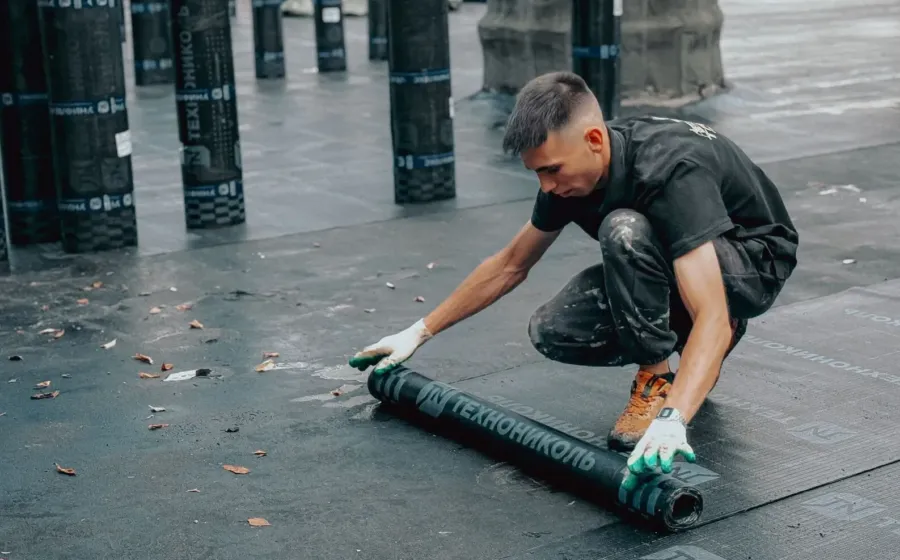 Tukang bangunan sedang memperbaik bagian atap rumah bocor menggunakan cat waterproofing